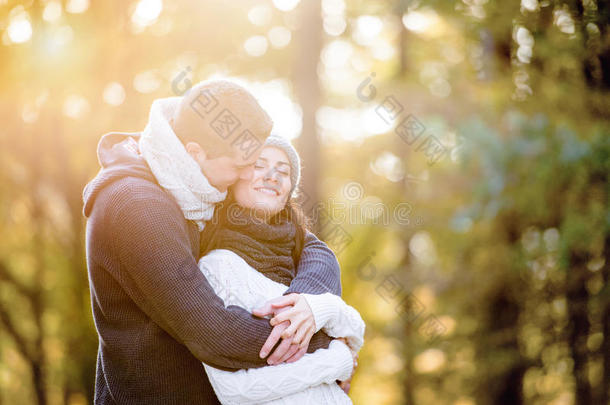 美丽的年轻夫妇拥抱和亲吻。 阳光明媚的秋天自然。