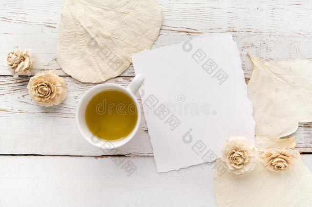 白色木桌上的花，空白的书页和一杯绿茶。 文本的自由空间。 上面的风景