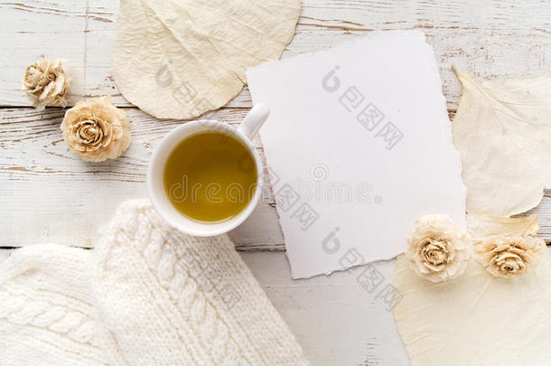 一杯带手套、花和白木背景的空白卡的茶