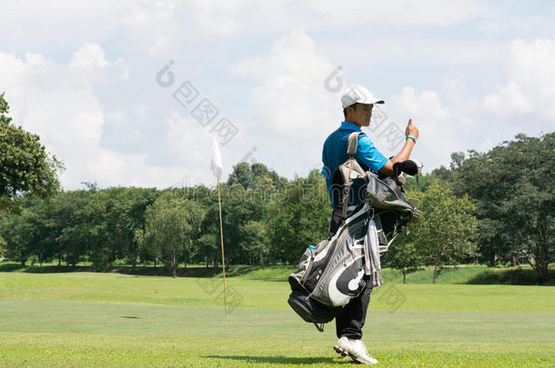 英俊的亚洲高尔夫球员男人带着他的包在高尔夫球场上