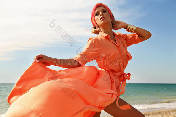 华丽的女人穿着豪华的衣服，在夏天的海滩上摆姿势