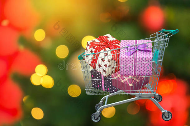 圣诞礼物和礼物丝带礼品盒在购物车与模糊的灯光