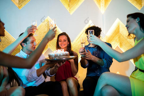 一群微笑的朋友在庆祝生日的时候品尝一杯香槟