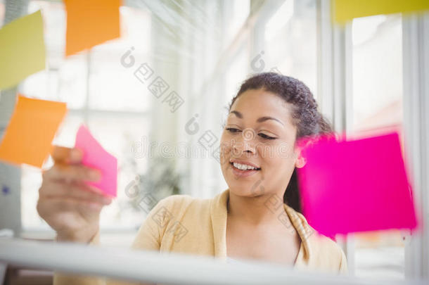 女商人在创意办公室的玻璃窗上贴着不干胶的纸条