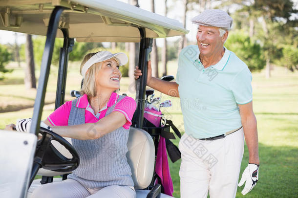 高尔夫球手女人坐在高尔夫球车上看男人