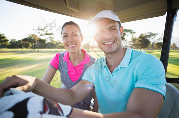 自信的高尔夫选手夫妇坐在高尔夫球车里