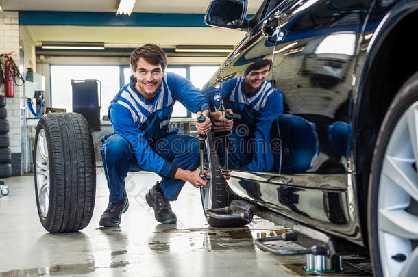 自信的机械师在车库更换汽车轮胎