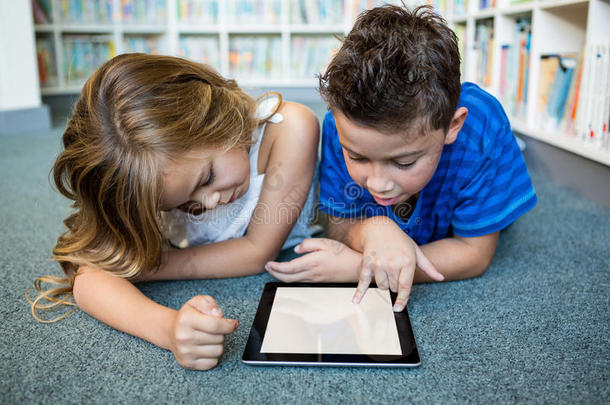 女孩和男孩在学校图书馆使用数字平板电脑