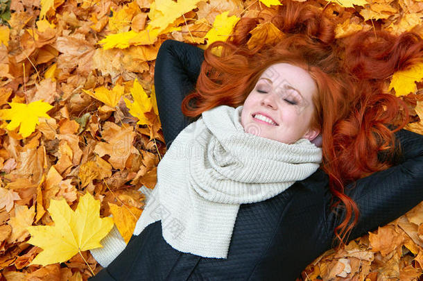 女孩躺在秋天森林背景的黄色落叶上