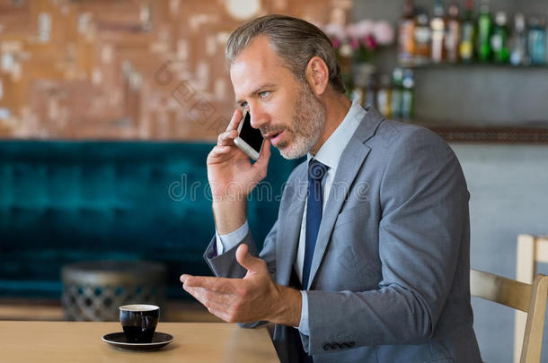 商人一边喝茶一边用手机说话