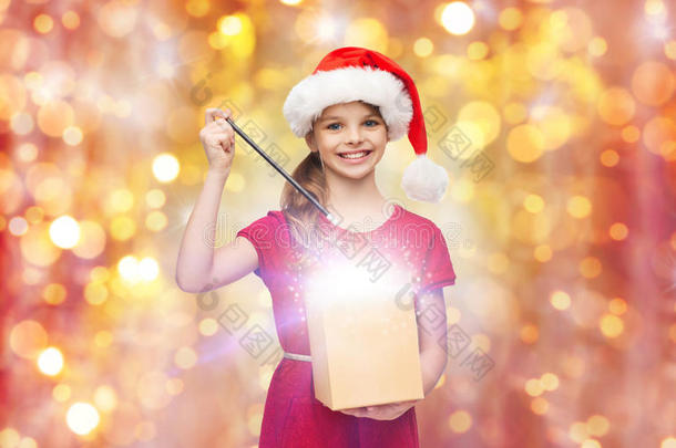 戴着圣诞老人帽子的女孩带着礼品盒和魔杖