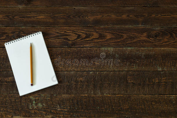 带笔记本和铅笔的棕色木桌。 上面的风景