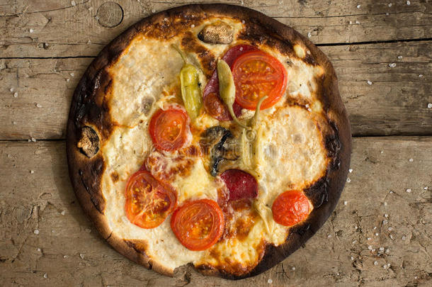 烧过的披萨，有西红柿、意大利腊肠、木纹香肠