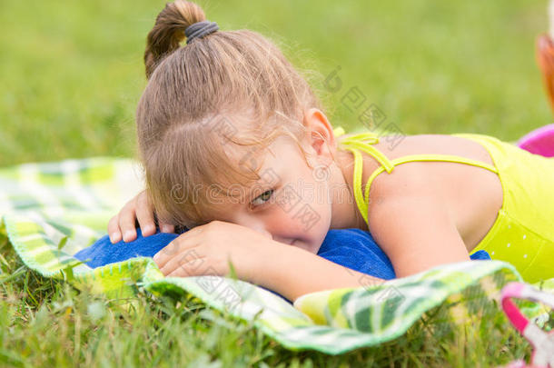 五岁的女孩躺在绿色草地<strong>上</strong>的<strong>一张</strong>床<strong>上</strong>，巧妙地看向<strong>一</strong>边