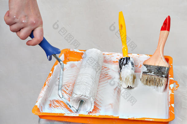 手画家扣篮滚筒刷在托盘的白色油漆。