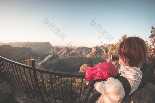 布莱德河峡谷，南非著名的旅游目的地。 游客在日落时从露台上用智能手机拍照