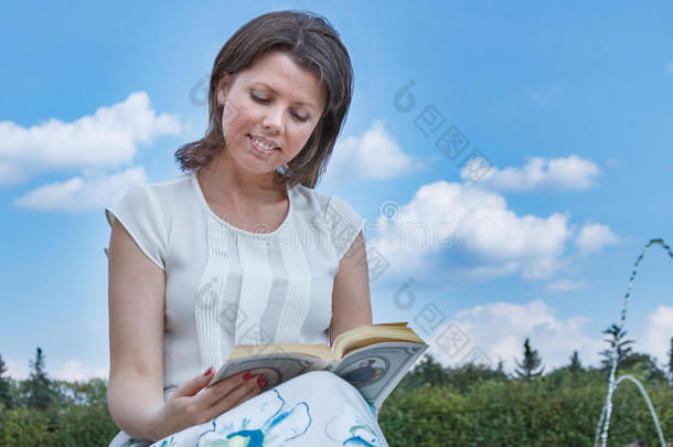 时尚漂亮的年轻时髦女人坐着读一<strong>本书</strong>穿衬衫长裙
