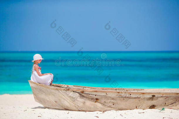 暑假期间海滩上穿着白色连衣裙的可爱小女孩