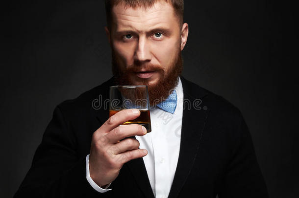 穿着西装和领带的优雅男人在工作室喝威士忌
