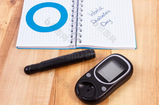 <strong>血糖</strong>仪，世界糖尿病日写在笔记本和蓝色圆圈，糖尿病的象征