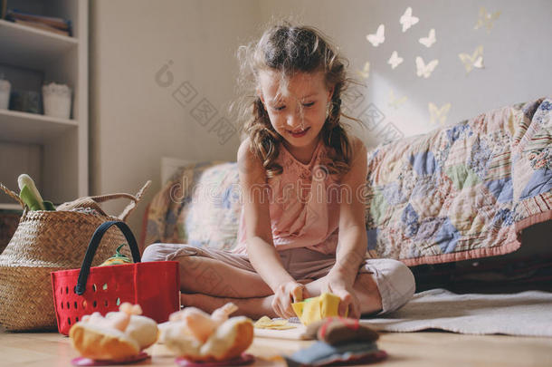 可爱的小女孩在她的房间里玩玩具食物，做饭，在家玩得开心