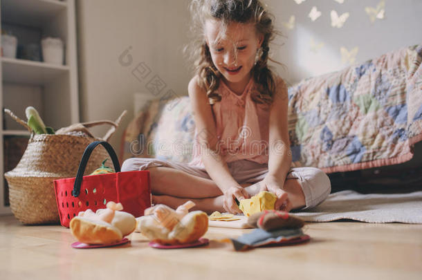 可爱的小女孩在她的房间里玩玩具食物，做饭，在家玩得开心