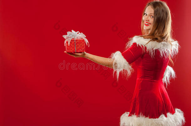 圣诞节，圣诞节，冬天，幸福的概念-微笑的女人戴着圣诞老人的帽子，带着礼品盒，红色背景。