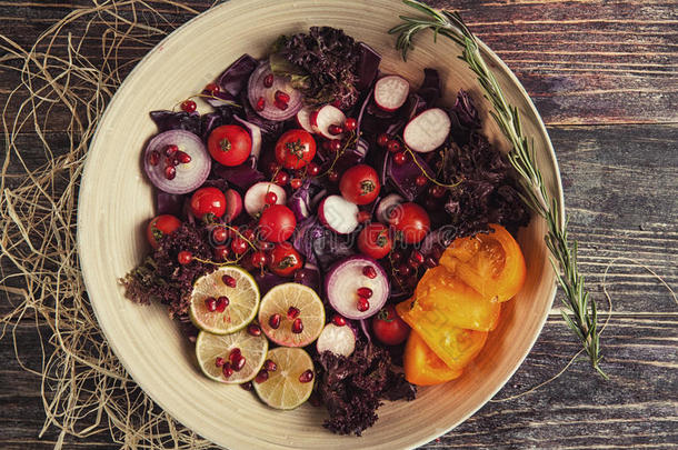 新鲜水果和蔬菜沙拉<strong>放</strong>在<strong>盘子</strong>里，或者<strong>放</strong>在木制桌子上，上面有西红柿、卷心菜、石榴、石灰、萝卜
