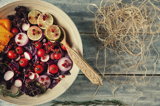 新鲜水果和蔬菜沙拉放在盘子里，或者放在木制桌子上，上面有西红柿、卷心菜、石榴、石灰、萝卜