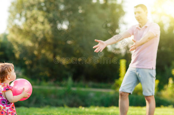 爸爸和小女儿在草坪上<strong>打球</strong>