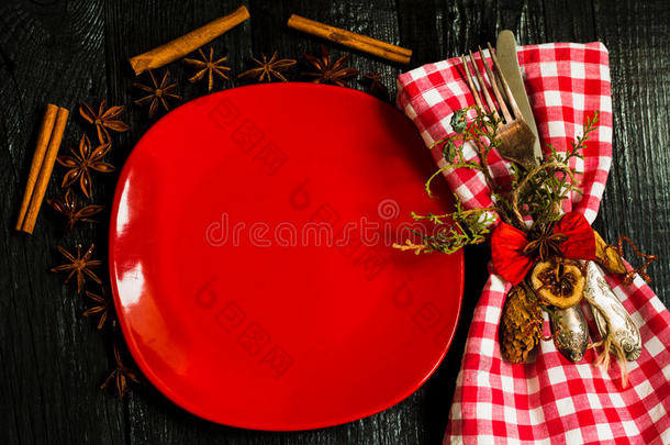 <strong>漂亮</strong>的圣诞餐具在一张<strong>红白相间</strong>的餐巾上，盘子里装着格子。 黑色木制背景。