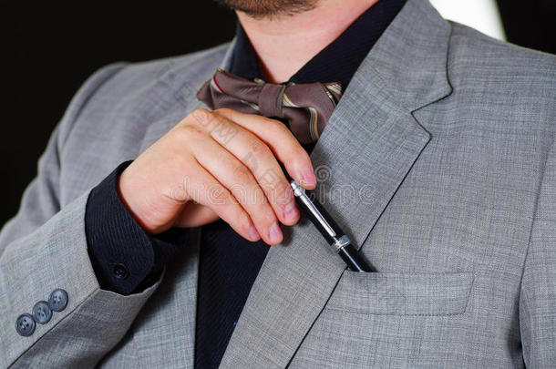 特写男子的胸部区域穿着正式的西装和领带，把钢笔放在夹克口袋里，男人穿衣服的概念