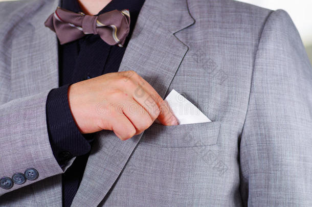 特写男人的胸部区域穿着正式的西装和领带，把纸巾放在夹克口袋里，男人穿衣服的概念