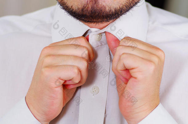 特写<strong>男人</strong>的胸部穿着白色衬衫，用手系领带，脸部分可见，<strong>男人穿衣</strong>服的概念