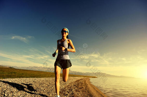 健身女子小径跑步者在日出海边跑步