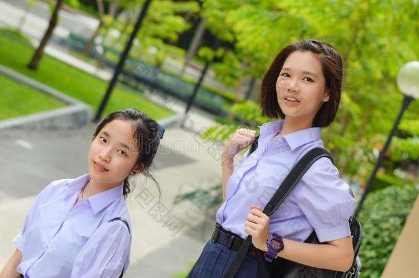 可爱的亚洲泰国高中女生夫妇穿着校服，和她的朋友站在一起，脸上<strong>洋溢</strong>着幸福的微笑