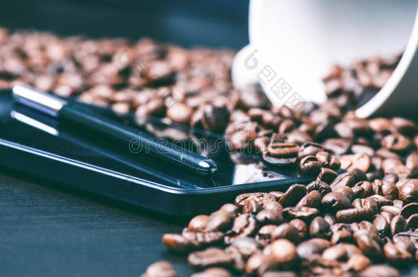 享受吧。 智能手机和原始咖啡背景上的手写笔。 吃咖啡豆。 收割。 自然背景。 LIF