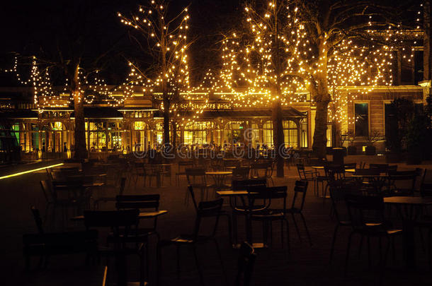 空夜餐厅，许多桌椅无人，神奇的仙女灯在树上，如圣诞节