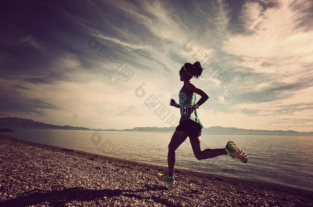 健身女子小径跑步者在日出海边跑步