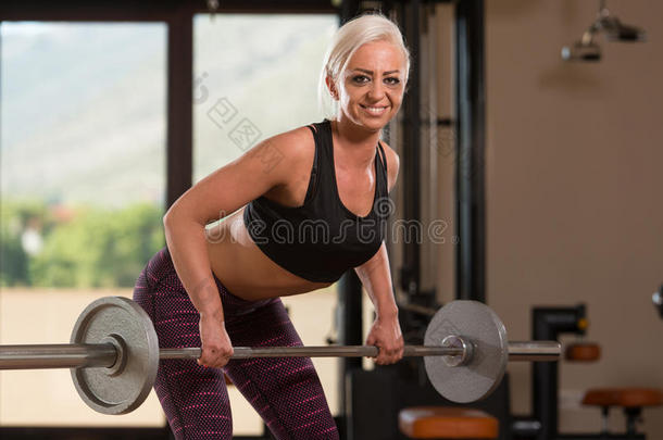 健身妇女使用杠铃锻炼回到健身房