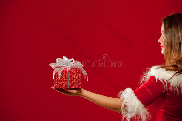 圣诞节，圣诞节，冬天，幸福的概念-微笑的女人戴着圣诞老人的帽子，带着礼品盒，红色背景。