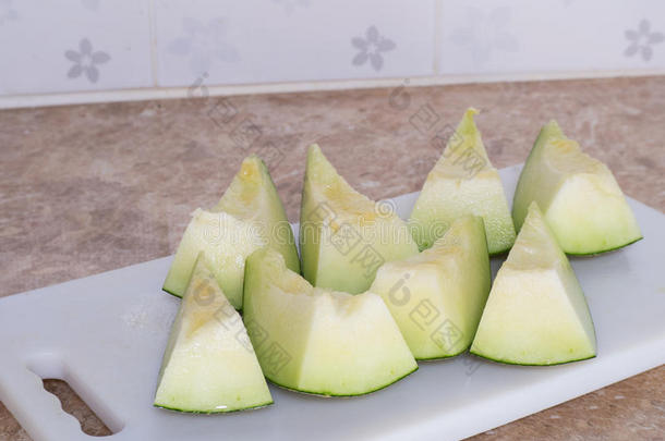 绿色的日本甜瓜被切割或分割在厨房的白色块上