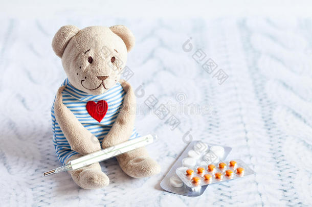 儿童软玩具泰迪熊与药丸测量水银玻璃温度计的温度。儿童疾病。