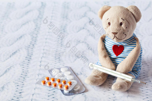 儿童软玩具泰迪熊与药丸测量水银玻璃温度计的温度。儿童疾病。