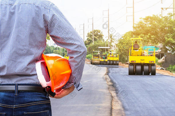 工程师在道路施工现场戴安全帽，用压路机工作沥青道路