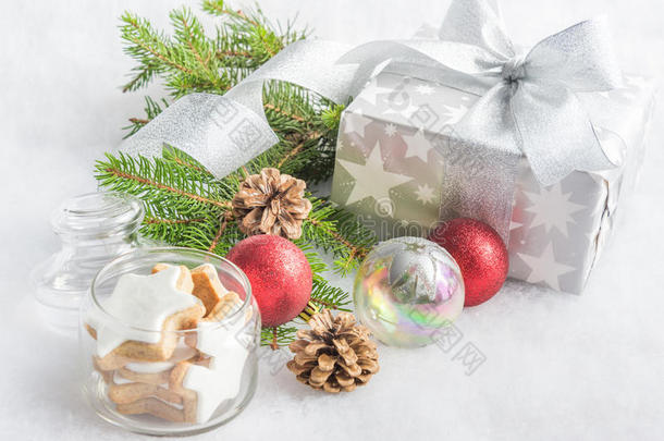 圣诞礼品盒，银色包装纸，白色蓬松的背景。 一个装满明星饼干和圣诞装饰的罐子。