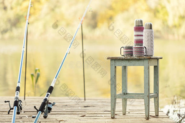 在河里钓鱼。 一根钓鱼竿和一个带杯子的热水瓶
