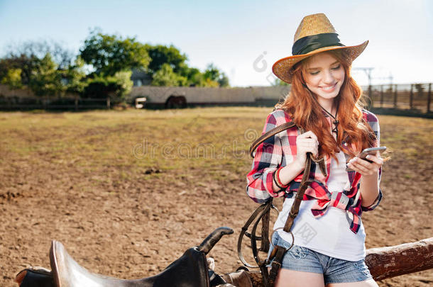 欢快的红头发年轻的女牛仔在<strong>村子</strong>里用手机