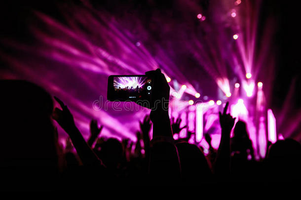 手持智能手机记录现场音乐节，拍摄音乐会舞台照片