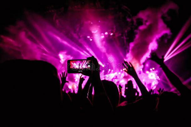 手持智能手机记录现场音乐节，拍摄音乐会舞台照片